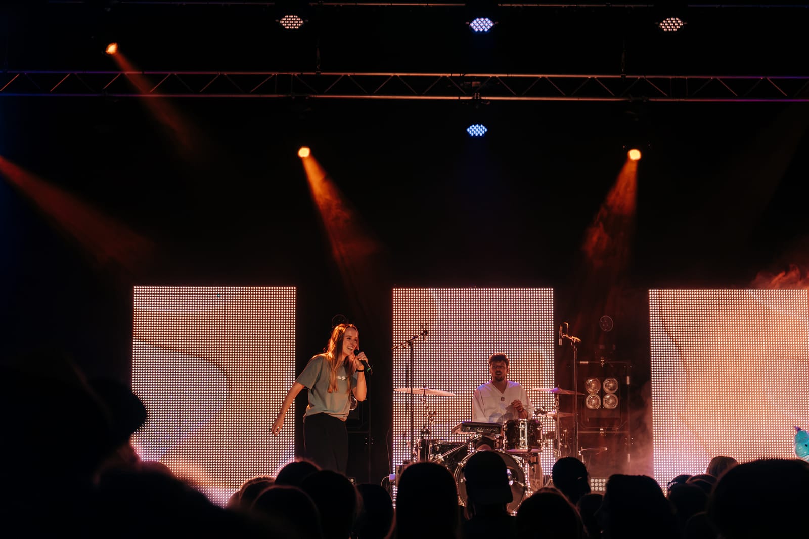 Toni Speer performing on stage under warm amber light.